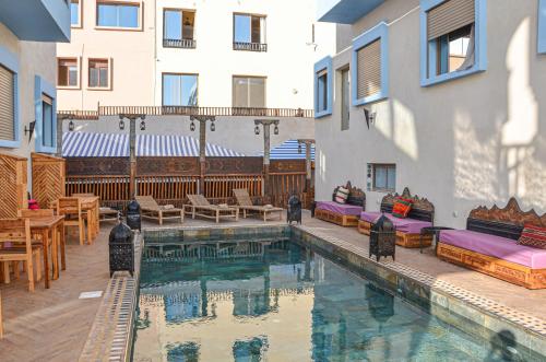 a hotel swimming pool with tables and chairs next to a building at Imsouane WOOD HOUSE in Imsouane