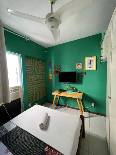a green room with a bed and a desk with a computer at CasAMARelo Hostel in Salvador