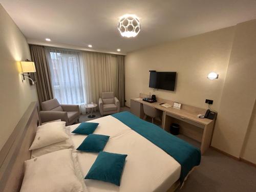 a hotel room with a large bed with blue pillows at Hotel Siesta in Užice