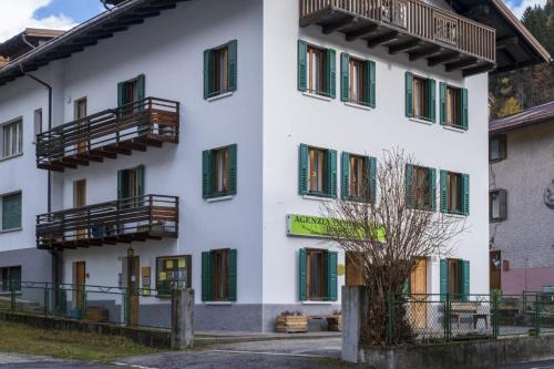 a white building with green windows and balconies at Appartamento Dolomiti Dream 1 in Falcade