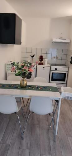 une cuisine avec une table, des chaises et un vase de fleurs dans l'établissement GabiHome, à Mulhouse