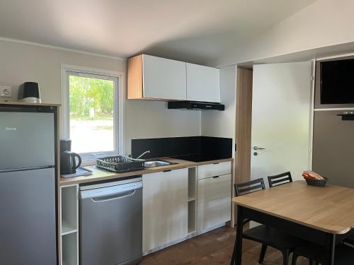 a kitchen with white cabinets and a wooden table at Camping de Saulieu in Saulieu