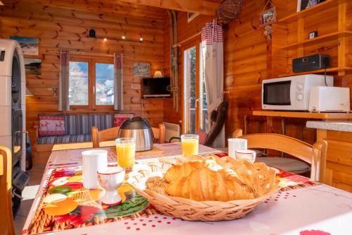 - une table à manger avec un panier de pain et du jus d'orange dans l'établissement Chalet Terrasse Plein Sud, Cheminée, Ski-Rando, Nature & Village, Animaux admis, Parking, à La Bresse
