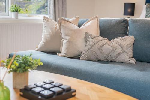 a blue couch with pillows and a remote control on a table at Chapel Lodge in Ambleside