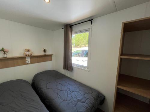 a small room with a bed and a window at Camping de Saulieu in Saulieu