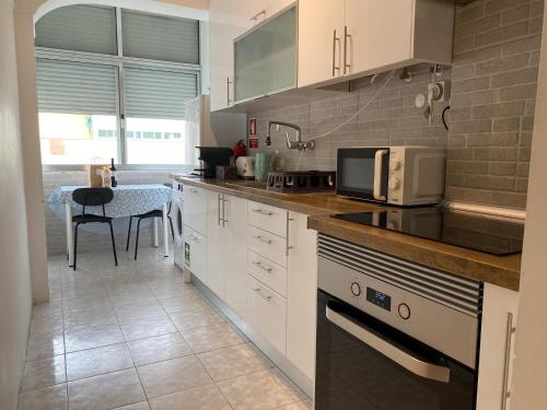 a kitchen with white cabinets and a counter top at Barreiro Central Apartment in Barreiro
