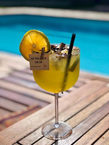 a drink sitting on a table next to a pool at Pousada Puerta Del Sol Rio das Ostras in Rio das Ostras