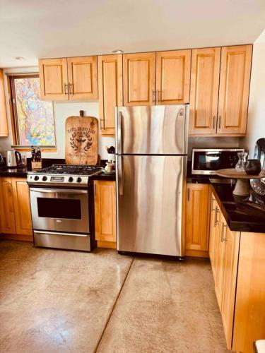 a kitchen with a stainless steel refrigerator and wooden cabinets at CASA TUA SANTA FE 2BR 2BA Design Loft Yoga studio Outdoor Living in Santa Fe