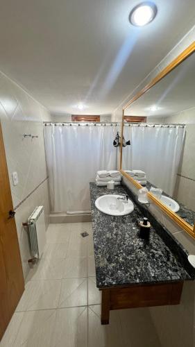 a bathroom with a sink and a mirror at Hotel y Cabañas Casa de Piedra in Trevelin