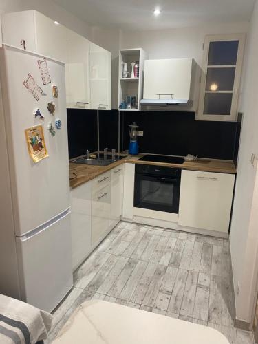  La cuisine est équipée de placards blancs et d'un réfrigérateur. dans l'établissement Magnifique T2 Toulouse centre, à Toulouse