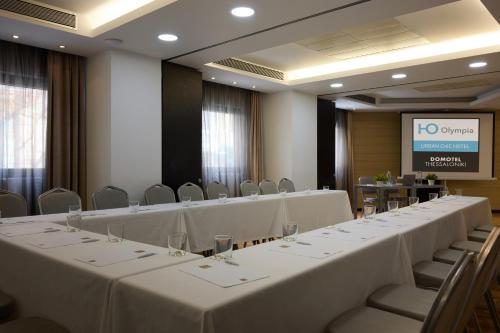 a conference room with white tables and chairs and a screen at Domotel Olympia in Thessaloniki