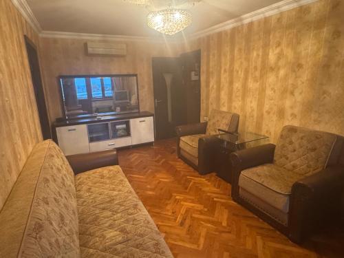 ein Wohnzimmer mit zwei Stühlen und einer Couch und einem Fernseher in der Unterkunft Home in Baku