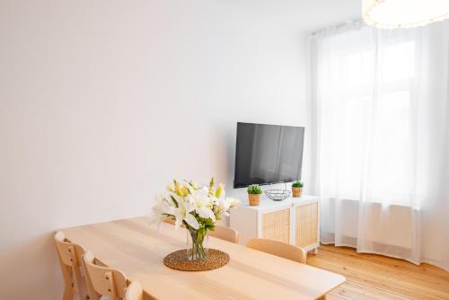 a dining room with a table with a vase of flowers at Arbio Monteurzimmer Fredersdorf parking included in Altlandsberg-Süd