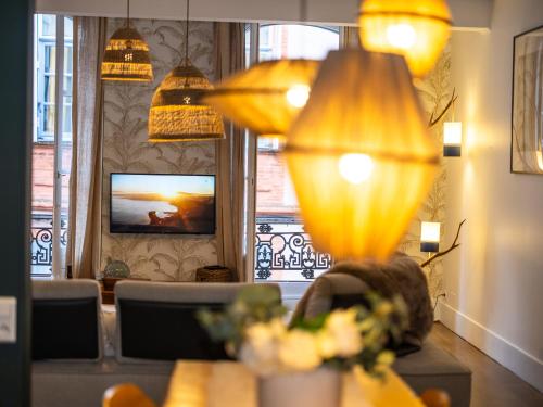 a living room with a television and a table with a lamp at Le Duplex Gourmand - Clim et parking - WiFi in Montauban