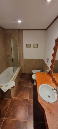 a bathroom with two toilets and a sink and a tub at El Pueblito Iguazú in Puerto Iguazú