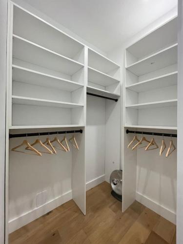 a walk in closet with white shelves and wooden floors at Stunning Family Style Duplex in New York