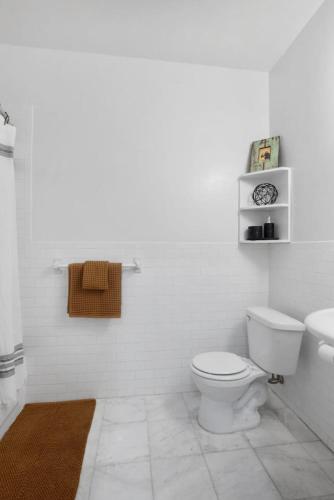 a white bathroom with a toilet and a sink at Charming Central Park Townhome in New York