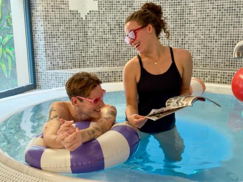 une femme et un homme dans une piscine dans l'établissement Golden Tulip Amnéville - Hôtel Spa & Casino, à Amnéville