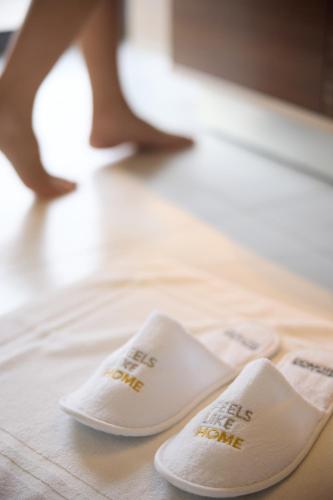 two white slippers sitting on top of a bed at Domotel Olympia in Thessaloniki