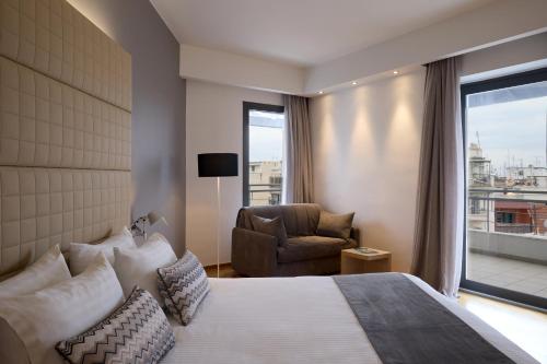 a hotel room with a bed and a chair and a window at Domotel Olympia in Thessaloniki