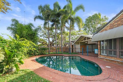 a swimming pool in front of a house with palm trees at Spacious Affordable 7B3B 2 Living Pool Yard and Mall in Brisbane