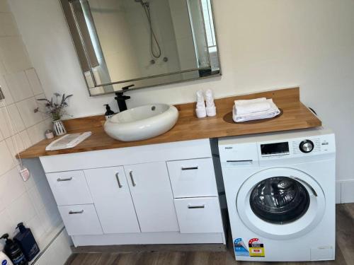 a bathroom with a sink and a washing machine at Cozy 2Beds Studio witch Kitchen Laundry near Zoo and Mall in Jindalee