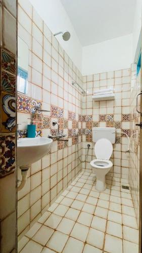 a tiled bathroom with a toilet and a sink at Jaladarshini Lakeside Gardens in Kollam