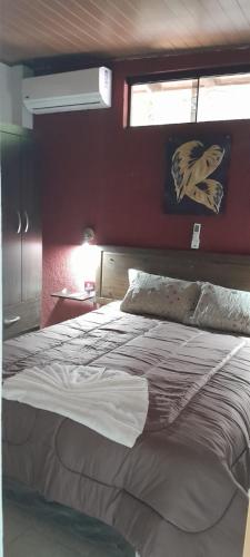 a bedroom with a large bed with a red wall at Apartamento la Colina de Sajonia solo efectivo guaranies in Asunción