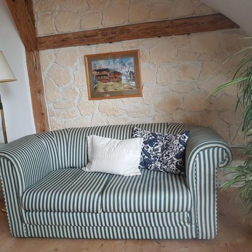 a striped couch with pillows on it in a room at Ferienwohnung 1880 in Burggen
