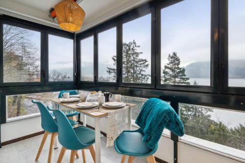 a dining room with a table and chairs and windows at 4 Seasons Apartment I 1-4 Personen I See, Bergsicht I 65'' Smart TV, Tischkicker und Badewanne I Parkplatz in Ingenbohl