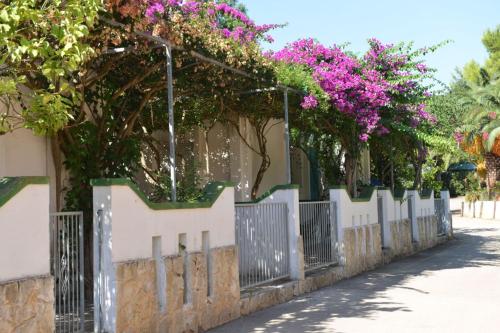 a fence with pink flowers on top of it at Camping Villaggio Pineta Al Mare in Specchiolla 