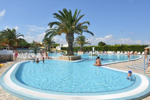 a large swimming pool with people in a resort at Camping Villaggio Pineta Al Mare in Specchiolla 