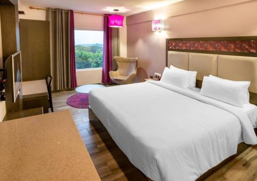 a hotel room with a large white bed and a window at Hotel Visakka Palani in Palani