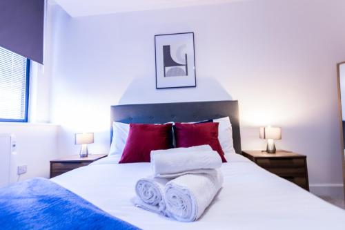 a bedroom with a white bed with towels on it at Trendy Apt in the Heart of MCR in Manchester