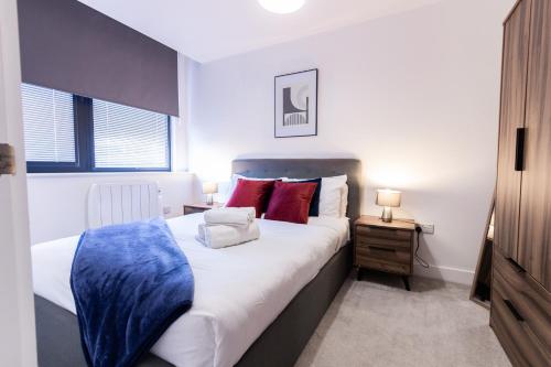 a bedroom with a large bed with red and blue pillows at Trendy Apt in the Heart of MCR in Manchester