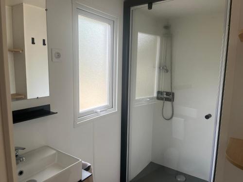 a white bathroom with a sink and a window at Camping de Saulieu in Saulieu