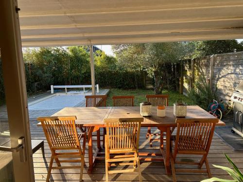 une table et des chaises en bois sur une terrasse dans l'établissement Villa avec piscine, à La Teste-de-Buch