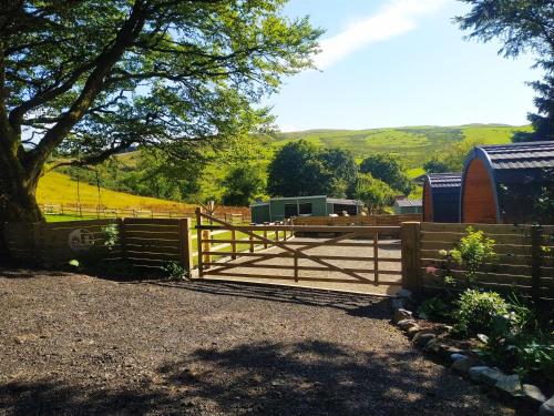 a wooden fence with a gate in front of a field at little peru luxury pods and alpaca farm in Crosshill