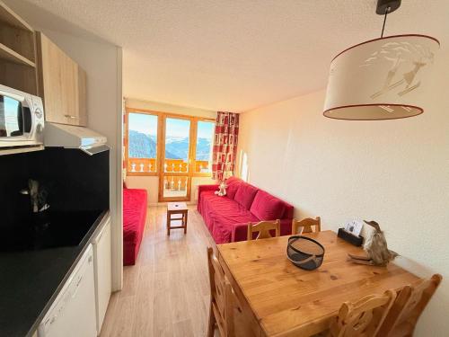 un salon avec une table et un canapé rouge dans l'établissement Résidence Licorne BELLE PLAGNE, à La Plagne Tarentaise