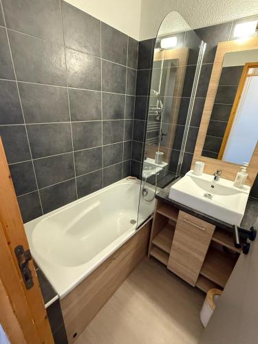une salle de bain avec une baignoire blanche et un lavabo dans l'établissement Résidence Licorne BELLE PLAGNE, à La Plagne Tarentaise