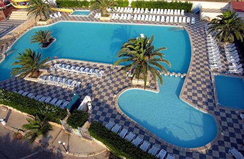 an overhead view of a swimming pool with chairs and palm trees at Camping Villaggio Pineta Al Mare in Specchiolla 