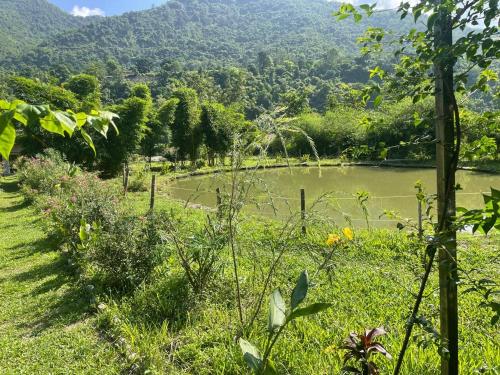 a field with a lake and mountains in the background at Nayar Valley Retreat in Lansdowne