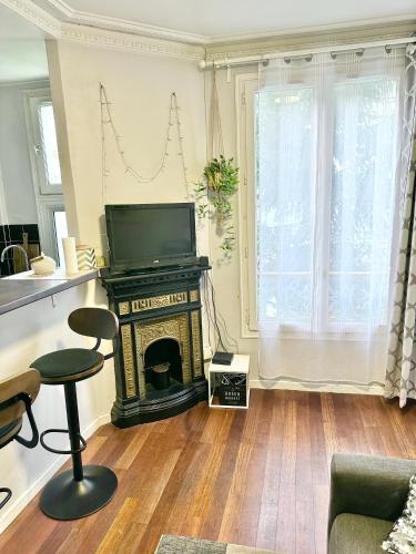 un salon avec une télévision et une cheminée dans l'établissement Appart cosy à 15 min des Champs-Elysées, à Levallois-Perret