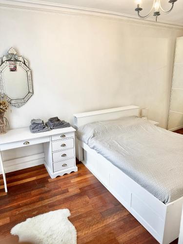 une chambre blanche avec un lit et un bureau dans l'établissement Appart cosy à 15 min des Champs-Elysées, à Levallois-Perret