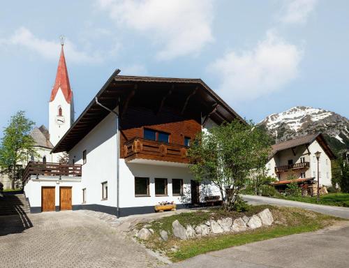 a white building with a church with a mountain at Villa Berwang in Berwang