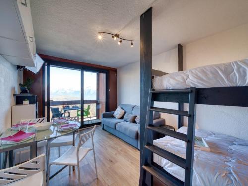 Cette chambre comprend des lits superposés, une table et un canapé. dans l'établissement Studio Soyouz Vanguard-104 by Interhome, au Corbier