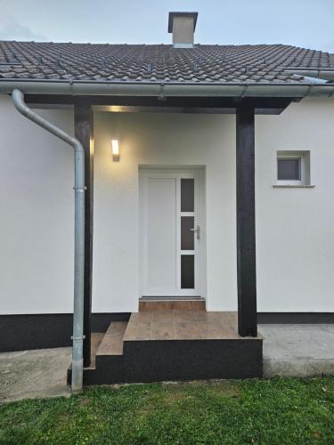 a white house with a white door and a porch at House Karla in Voćin