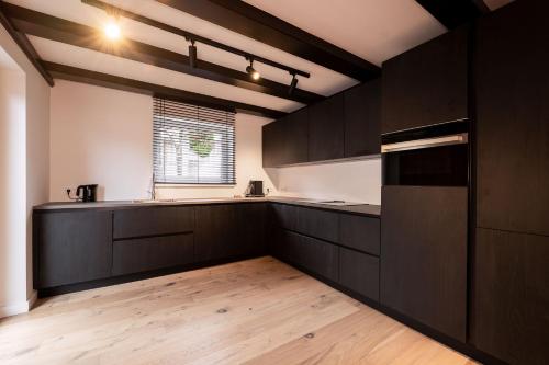 a kitchen with black cabinets and a wooden floor at Villa Berwang in Berwang