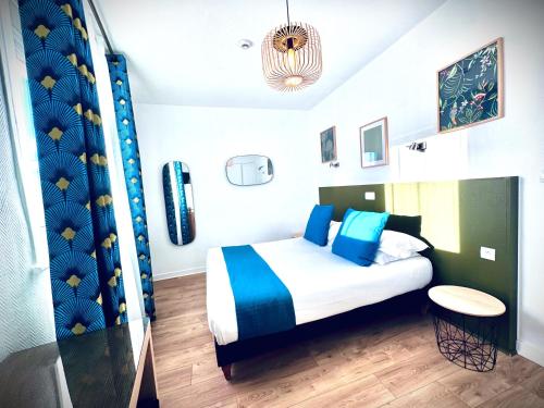 a bedroom with a bed with blue and white pillows at Hôtel Jules in Le Touquet-Paris-Plage