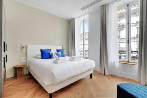 une chambre avec un grand lit blanc avec des oreillers bleus dans l'établissement Welcoming apartment - 2BR-6P - Opera, à Paris